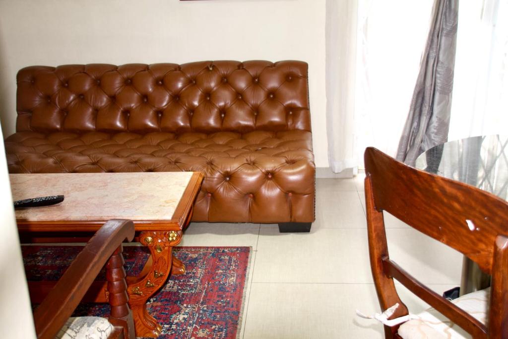 a brown leather couch in a living room with a table at Zenko Suave- 12 Madison West in Johannesburg