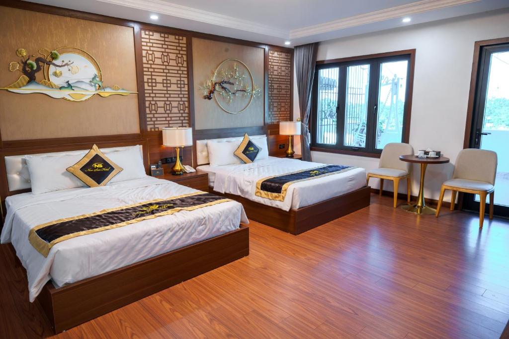 a hotel room with two beds and a table and chairs at New Sun Móng Cái Hotel in Móng Cái