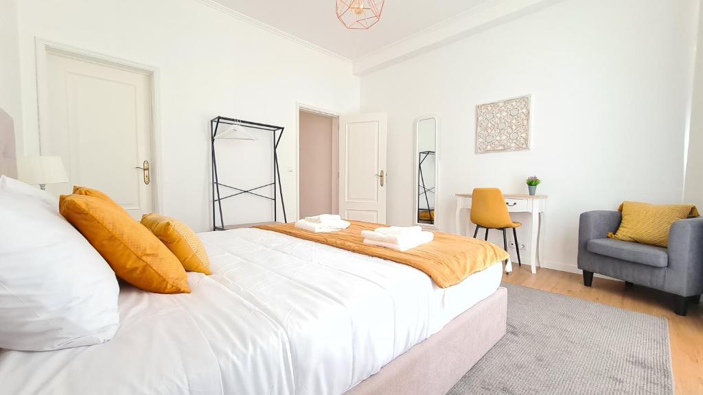 a white bedroom with a large bed and a chair at Santa Clara Apartments in Ponta Delgada