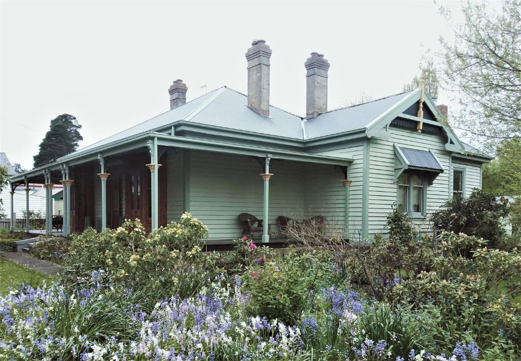 a green house with flowers in front of it at Oakdene Heritage Accommodation in Saint Marys