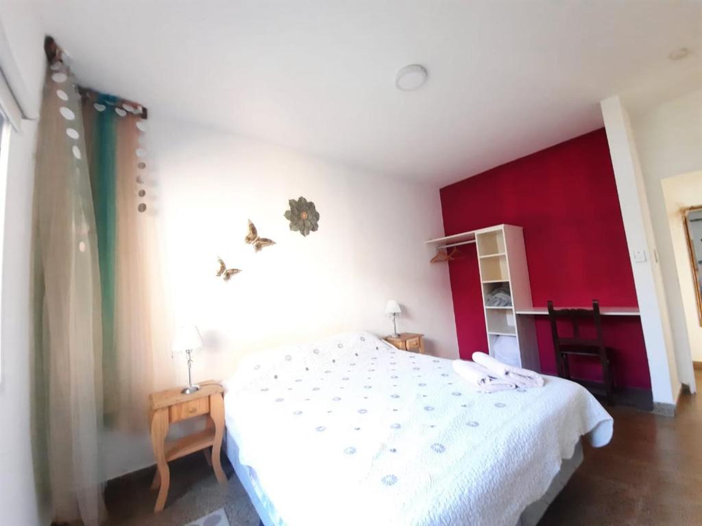 1 dormitorio con cama blanca y pared roja en Alma viajera en Posadas