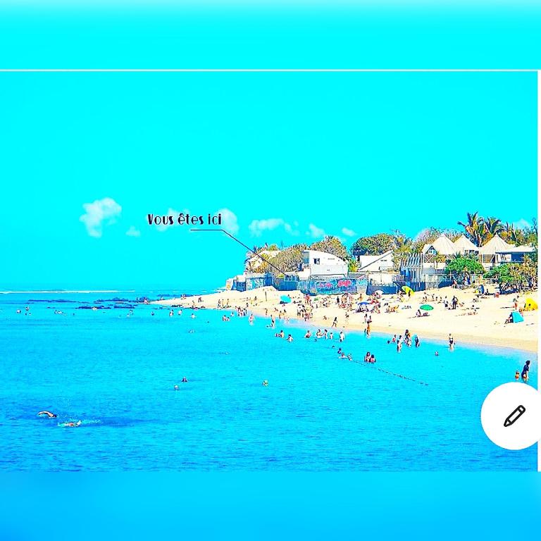 a view of a beach with people in the water at Villa Maimouna les pieds dans l'eau in Saint-Pierre