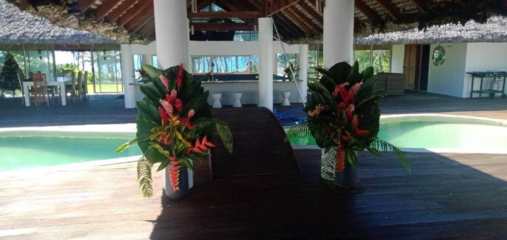 dos jarrones con flores en una mesa junto a una piscina en Solwata House, On the Water Sleeps 6, en Port Vila