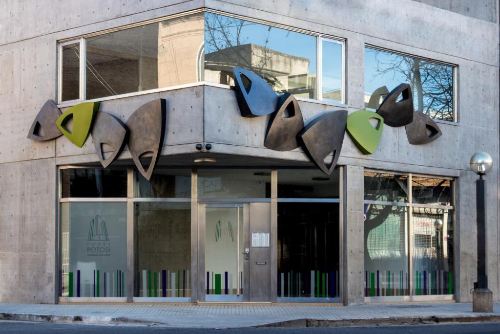 un magasin devant un bâtiment avec des sculptures sur celui-ci dans l'établissement Torre Potosi Departamentos, à Rosario