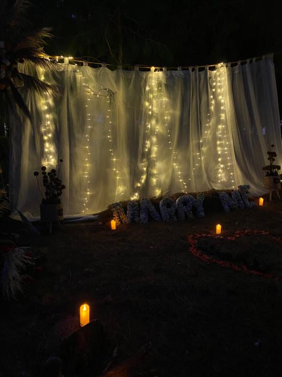 uma cortina branca com luzes acesas com velas em El Prado Glamping em Susudel  