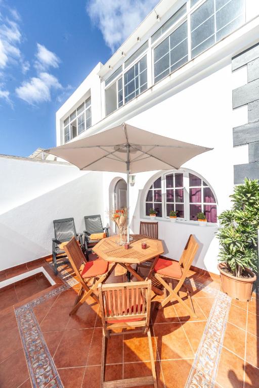 a patio with a wooden table and chairs and an umbrella at Luxury Beach Tanza in Playa Honda
