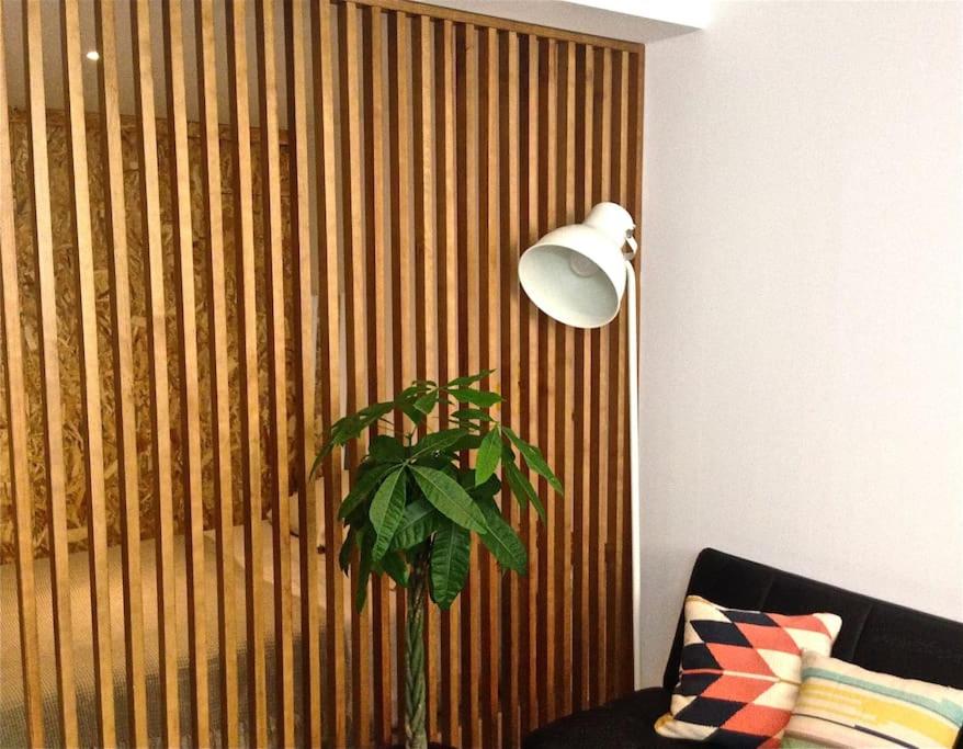 a lamp and a plant in front of a wooden wall at Casa da Travessa in Lisbon