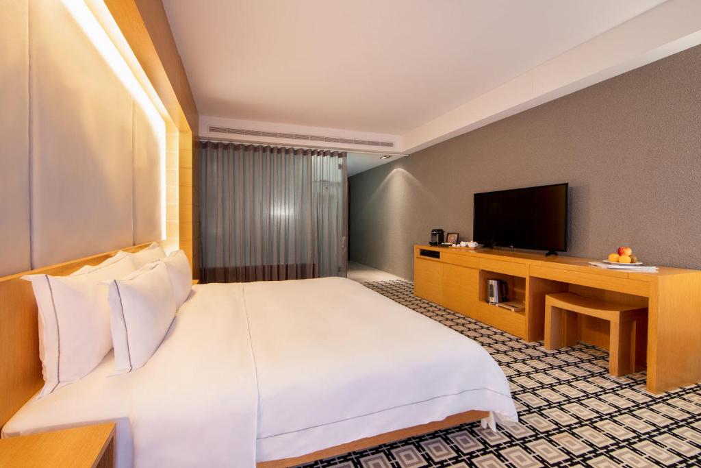 a hotel room with a bed and a television at Wulai Pause Landis Resort in Wulai