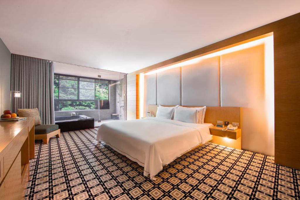 a bedroom with a large white bed and a window at Wulai Pause Landis Resort in Wulai
