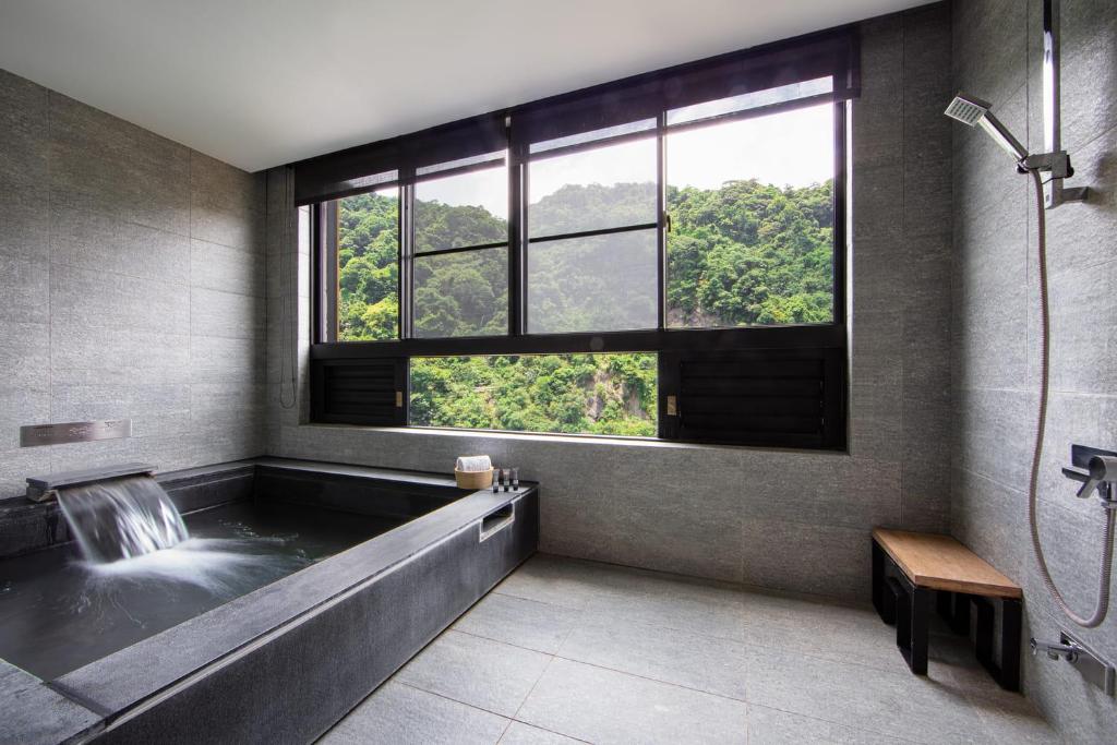 a bathroom with a large window and a tub with a waterfall at Wulai Pause Landis Resort in Wulai
