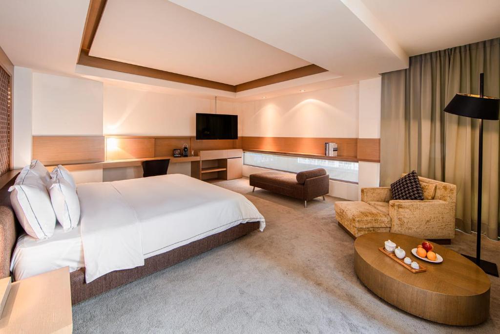 a hotel room with a bed and a living room at Wulai Pause Landis Resort in Wulai
