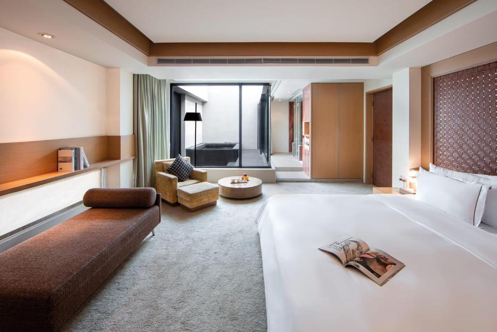 a hotel room with a large bed and a living room at Wulai Pause Landis Resort in Wulai