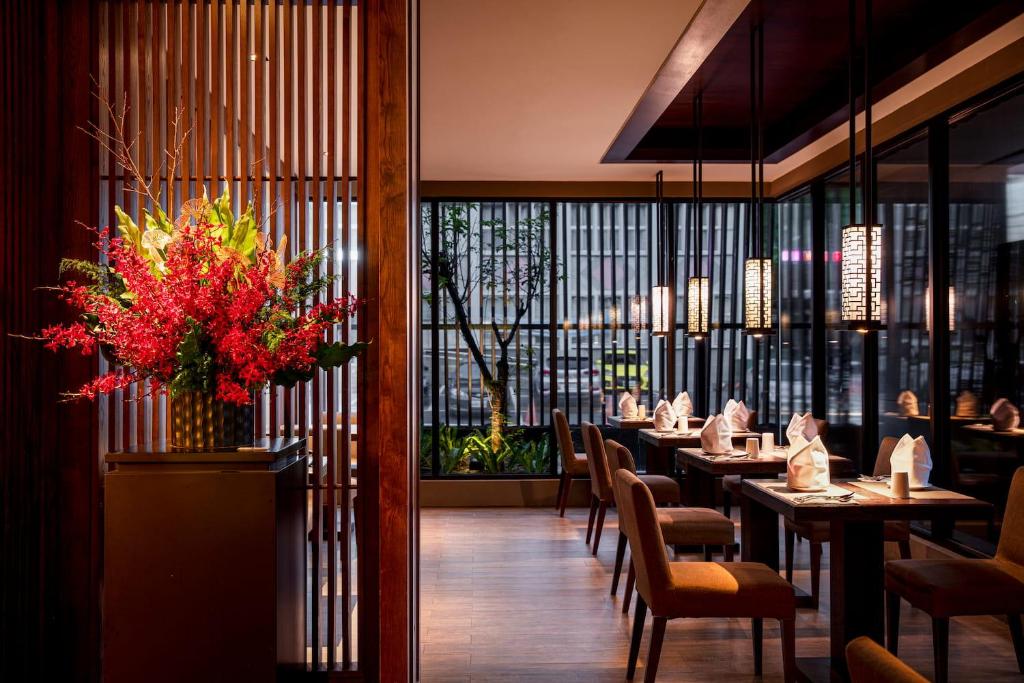 a restaurant with tables and chairs and a vase of flowers at Wulai Pause Landis Resort in Wulai