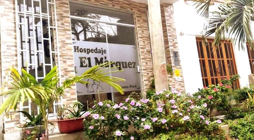 un panneau sur le côté d'un bâtiment avec des plantes dans l'établissement Hospedaje EL MARQUEZ Expat, à Máncora