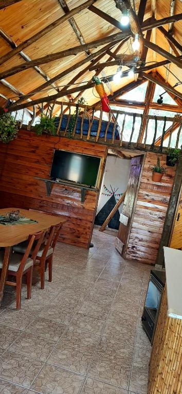 Habitación con mesa y TV en la pared. en Cabaña encantada en San Rafael