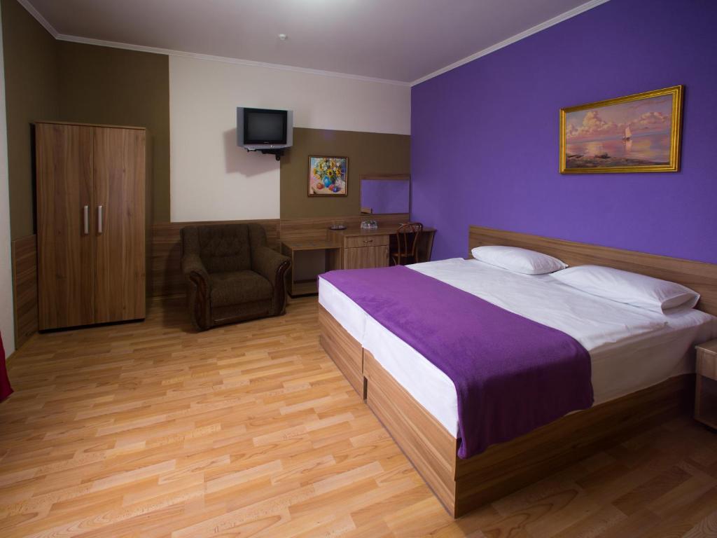 カームヤネツィ・ポジーリシクィイにあるGala Hotelの紫の壁のベッドルーム1室(大型ベッド1台付)