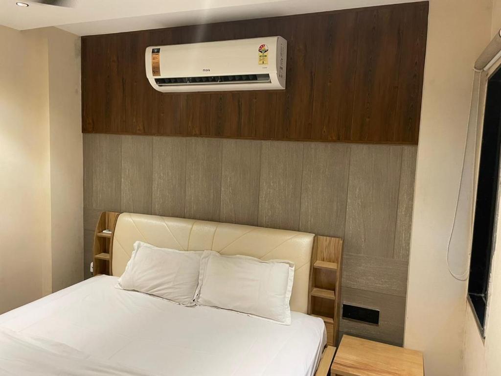 1 dormitorio con 1 cama blanca y aire acondicionado en Stay10 Studio Apartments en Indore