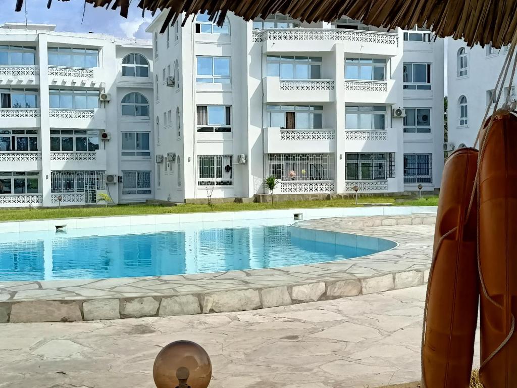 a swimming pool in front of a large building at PahaliMzuri Kijani - 1 Bedroom Beach Apartment with Swimming Pool in Malindi