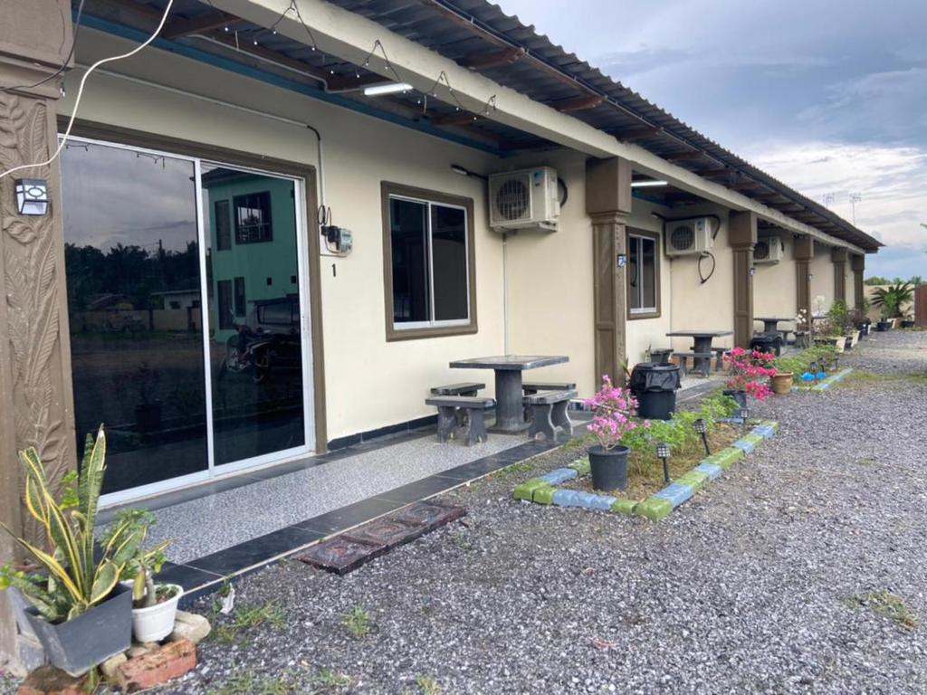 une maison avec une table et des plantes en pot devant elle dans l'établissement MAMA homestay, à Bagan Serai