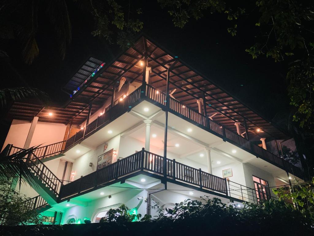 a white house with a balcony at night at Hiru Resort Inn Unawatuna in Unawatuna