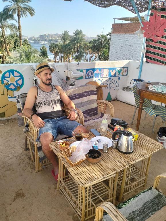 a man sitting in a chair next to a table at Roma House in Aswan