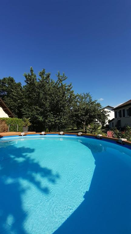 une grande piscine bleue avec des arbres en arrière-plan dans l'établissement Les Jardins de la quiétude, à Bettancourt-la-Ferrée