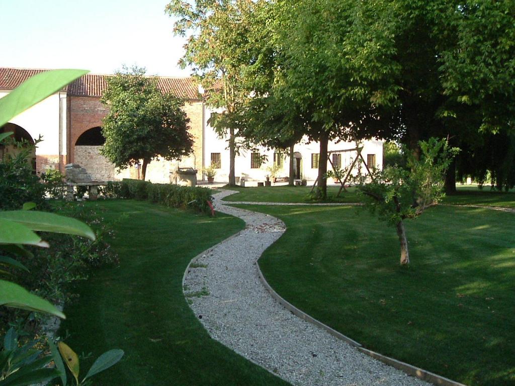 un sentiero ghiaioso in un parco alberato e in un edificio di Agriturismo La Sophora a Montegaldella