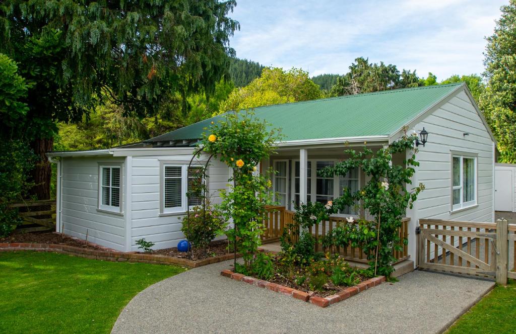a small white shed with a fence and a garden at Birdsong Cottage in Paraparaumu
