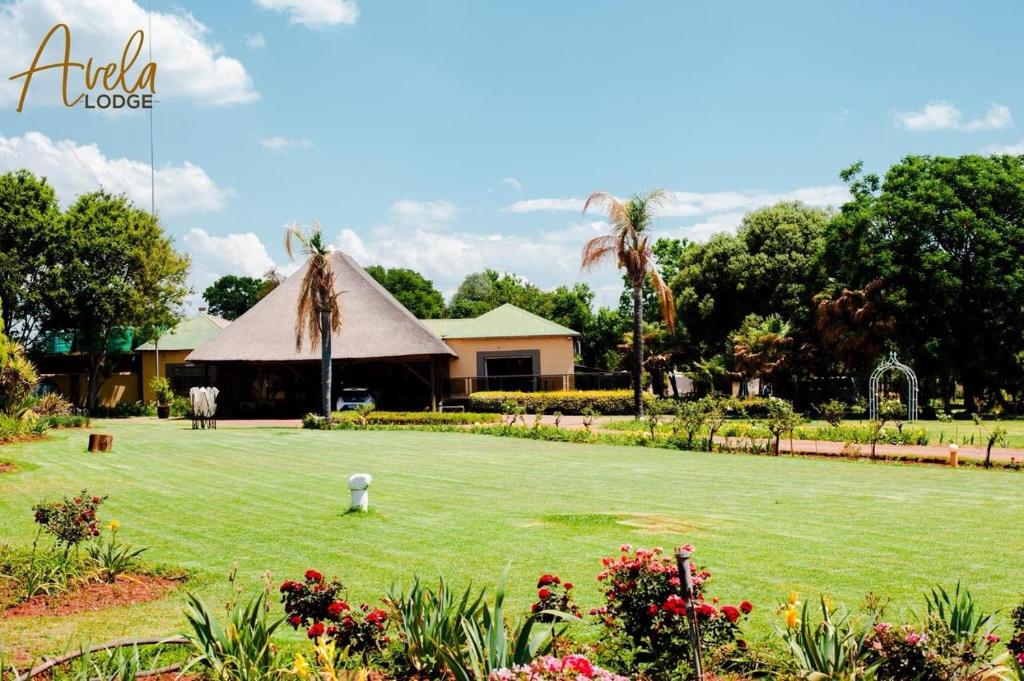 a large yard with a building with a thatch roof at Avela Lodge in Hekpoort
