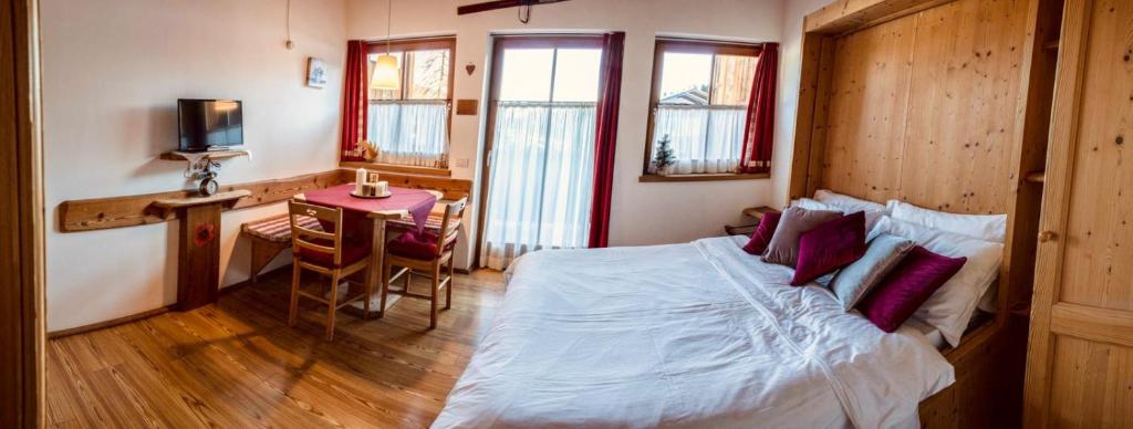 een slaapkamer met een bed, een bureau en een tafel bij Residence Valpiccola in Val di Zoldo