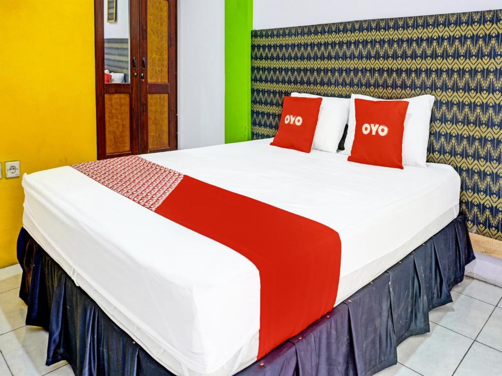 uma cama grande com almofadas vermelhas num quarto em OYO 91796 Guest House Ghalta Syariah em Karawang