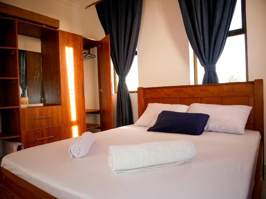 a bedroom with a white bed with blue curtains at Lux Suites Casey's Apartments Bamburi in Bamburi