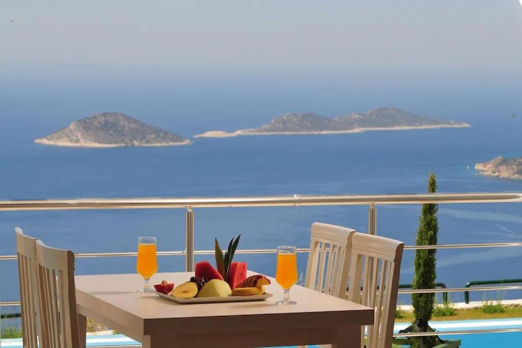 a table with a plate of fruit and two glasses of orange juice at Belvedere, LaVanta, Kalkan in Kalkan