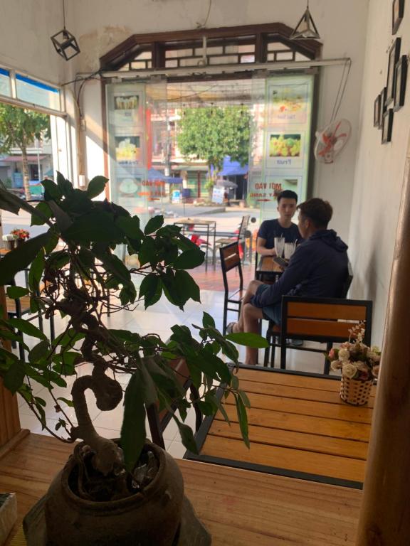 una pianta in vaso di fronte a un ristorante con due persone sedute di Phuong Linh Hotel a Bảo Lạc