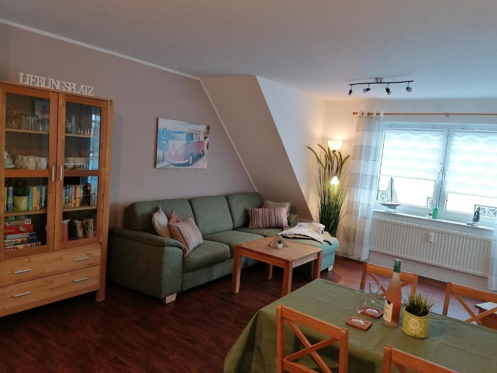 a living room with a green couch and a table at Fewo im Kastania Nr19 in Petersdorf auf Fehmarn