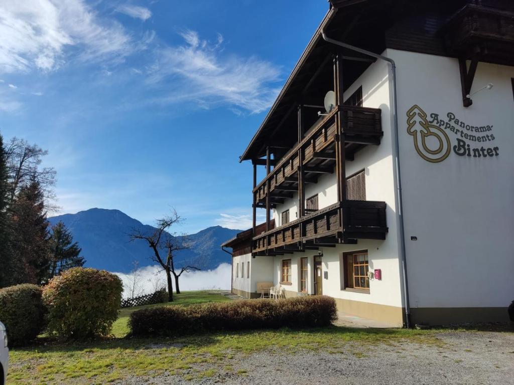 un edificio con balcón y montañas de fondo en Panorama Appartements Binter No. 1 en Hermagor