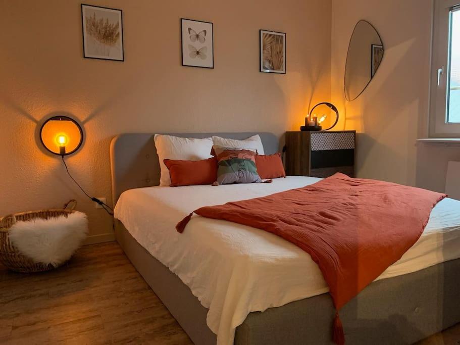 a bedroom with a bed with an orange blanket on it at La petite halte in Lemberg