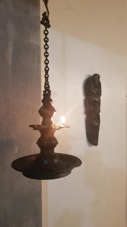 a chandelier with a candle and a mask on a wall at Ayubowan Holiday Home in Kandy
