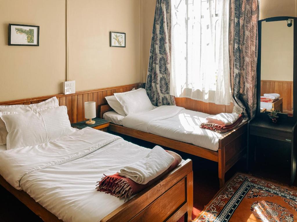 two twin beds in a room with a window at Cloud 9 - B&B in Kalimpong