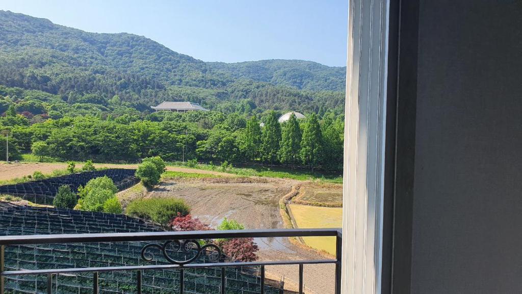 een balkon met uitzicht op een veld en de bergen bij Gamseong House in Sejong