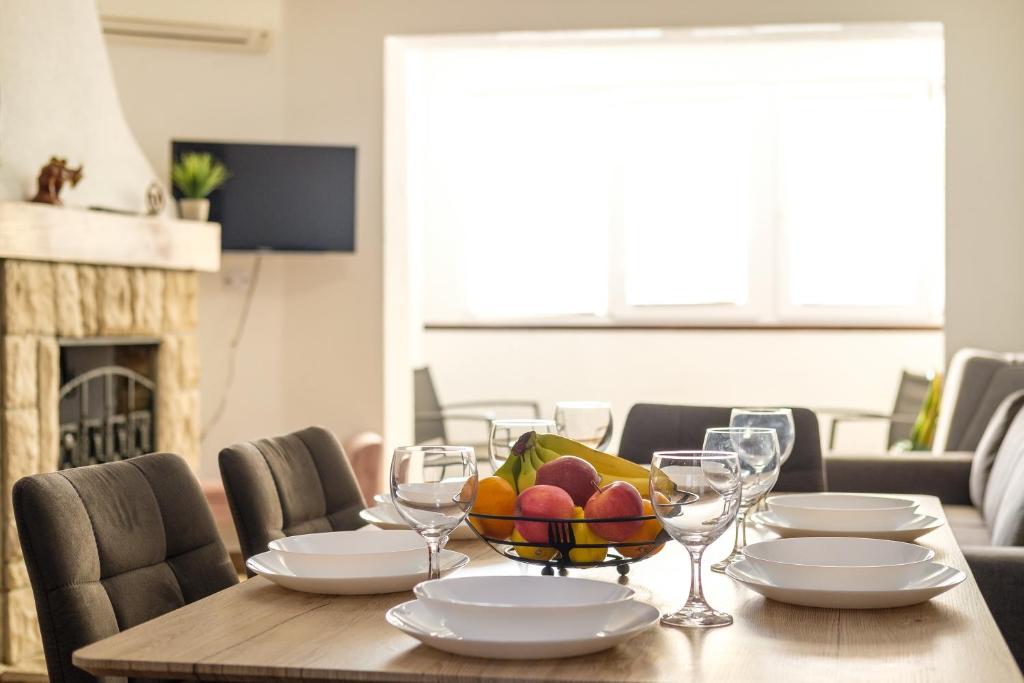 a table with a bowl of fruit and wine glasses at Apartment Molnar Crikvenica in Crikvenica