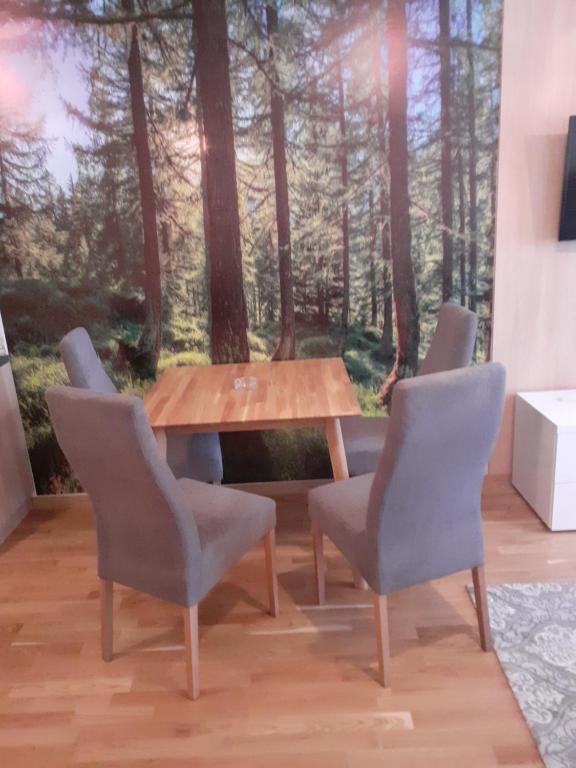 a wooden table with four chairs and a table in the woods at Apartman" AROMA 2 "Bjelasnica in Bjelašnica