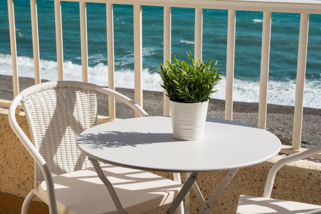 een witte tafel en stoelen op een balkon met uitzicht op de oceaan bij El Cachalote Feliz in La Rábita