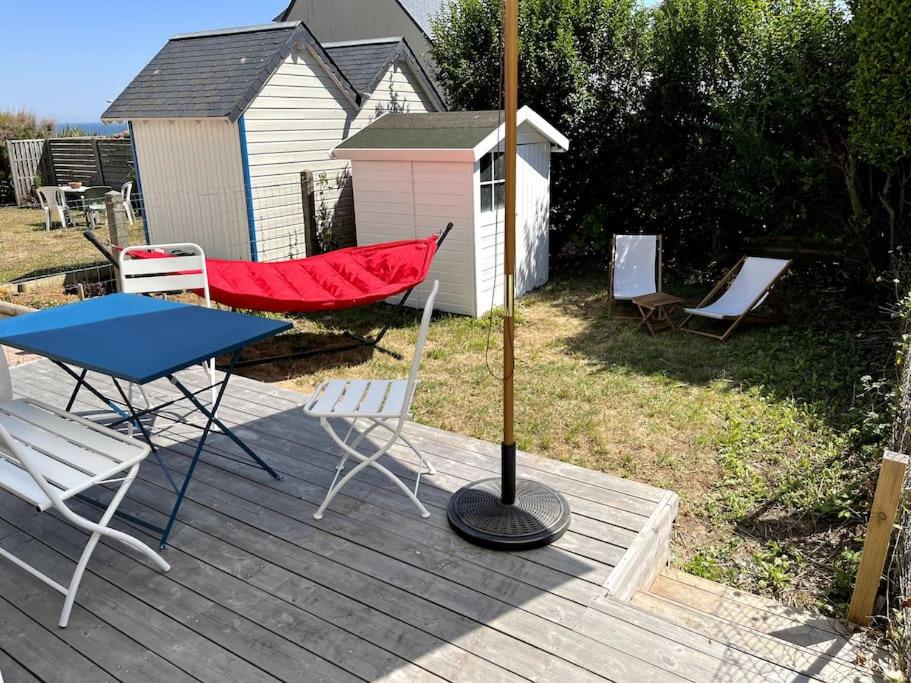 un patio con hamaca y sillas en una terraza en LA CABINE VUE MER en Luc-sur-Mer