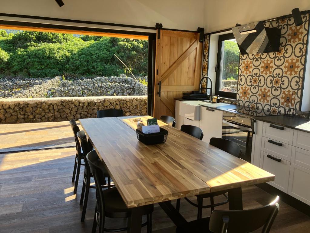 eine Küche und ein Esszimmer mit einem Tisch und einem großen Fenster in der Unterkunft Casa da Vinha Escondida AL in Biscoitos
