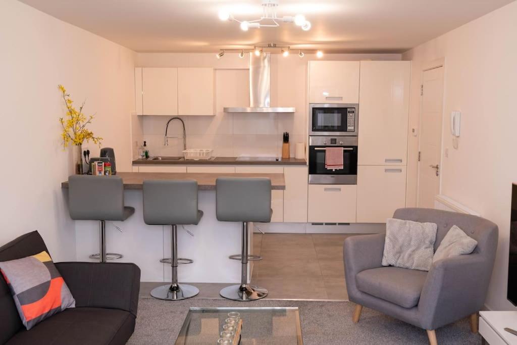 een woonkamer met een bank en stoelen en een keuken bij Panorama House, Modern 3-Bedroom Apartment 3, Oxford in Kidlington