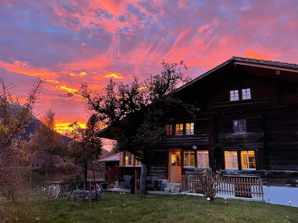 a wooden house with a sunset in the background at Chalet Brünig in Meiringen