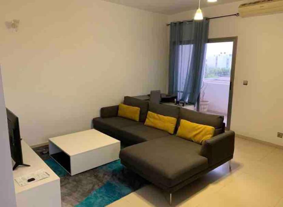 a living room with a black couch and yellow pillows at AYA Mermoz - Superbe appartement dans une résidence récente in Dakar