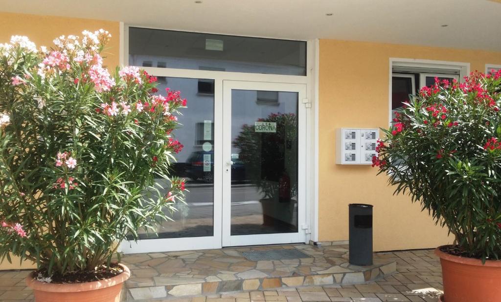 una puerta de cristal de un edificio con flores en macetas en Pension Corona, en Forst