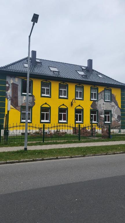 een geel gebouw met een schilderij aan de zijkant bij JaNettes Gästehaus in Bad Doberan